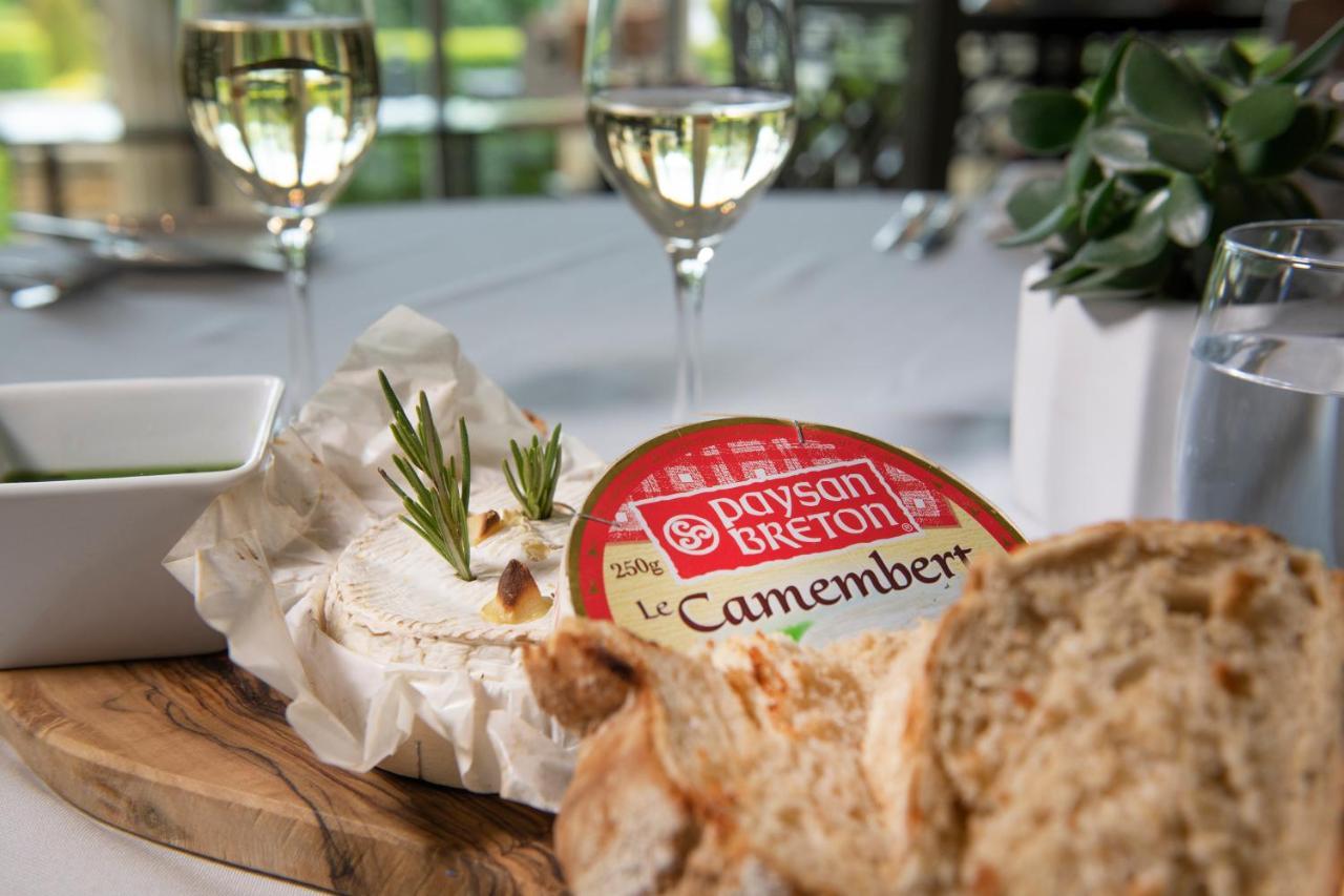 Macdonald Bath Spa Hotel Buitenkant foto The photo features a dining setting that includes a wooden platter with a round Camembert cheese, garnished with fresh rosemary sprigs. Nearby, there is a serving of bread, likely sliced, and a small bowl, potentially for dipping or spreading. In the