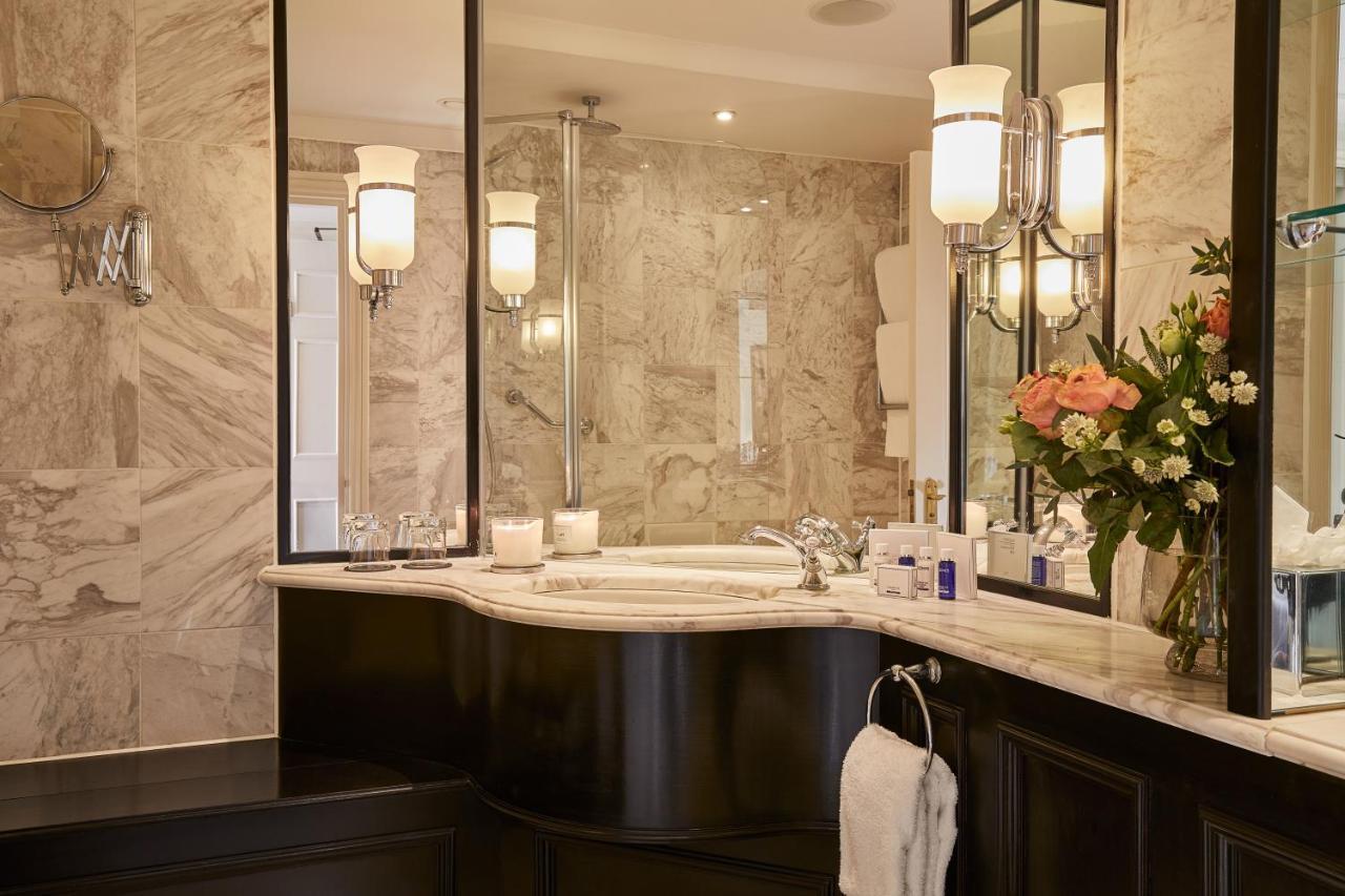 Macdonald Bath Spa Hotel Buitenkant foto The photo shows a luxurious bathroom featuring elegant design elements. There is a curved marble countertop with a sink, complemented by stylish silver fixtures. The walls are adorned with light-colored marble, creating a sophisticated ambiance. Seve