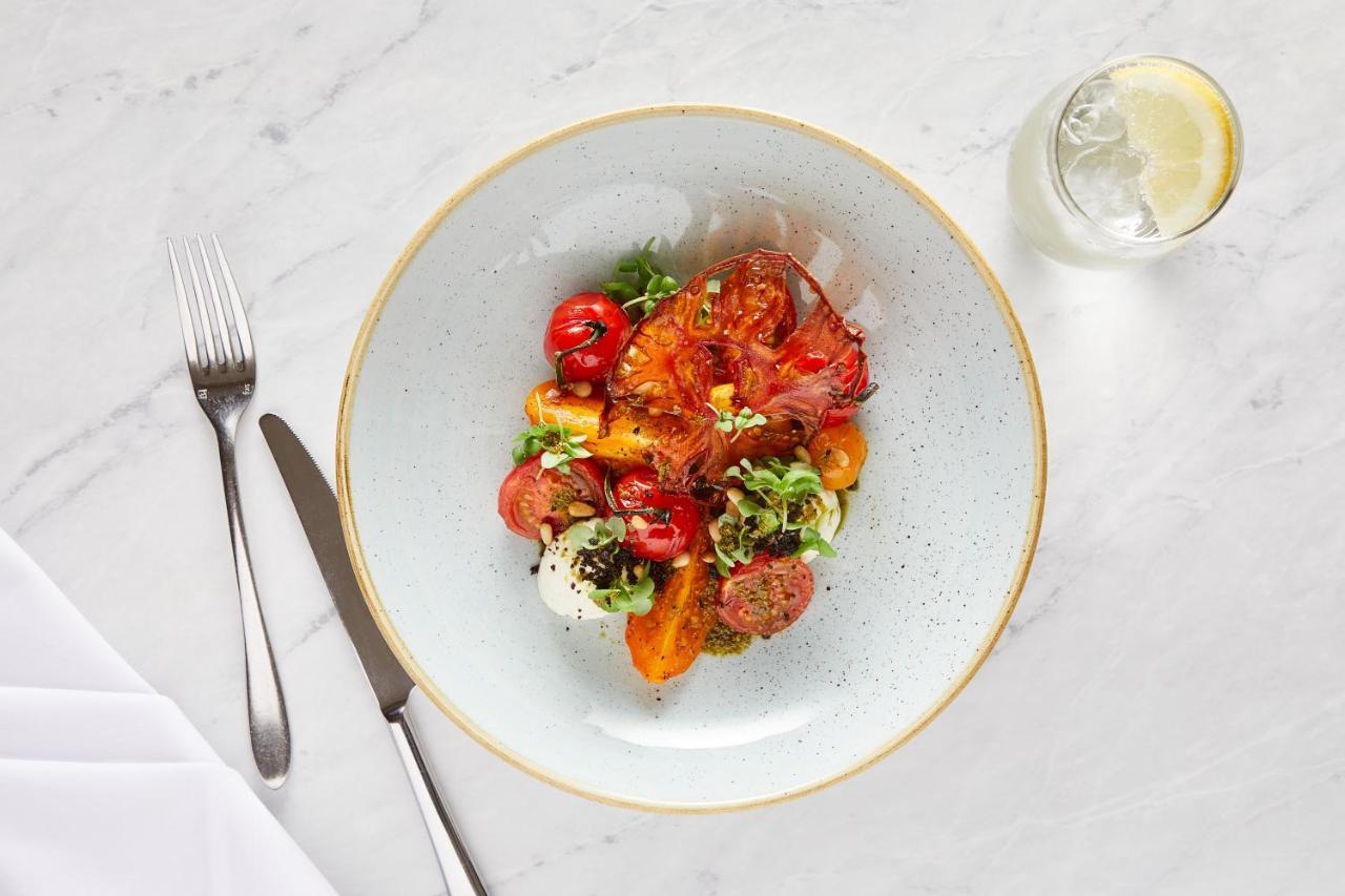 Macdonald Bath Spa Hotel Buitenkant foto The photo shows a beautifully arranged plate of food. The dish features a mix of colorful ingredients, including roasted or grilled vegetables, likely bell peppers and tomatoes, along with fresh greens. There are also some circular slices of another 