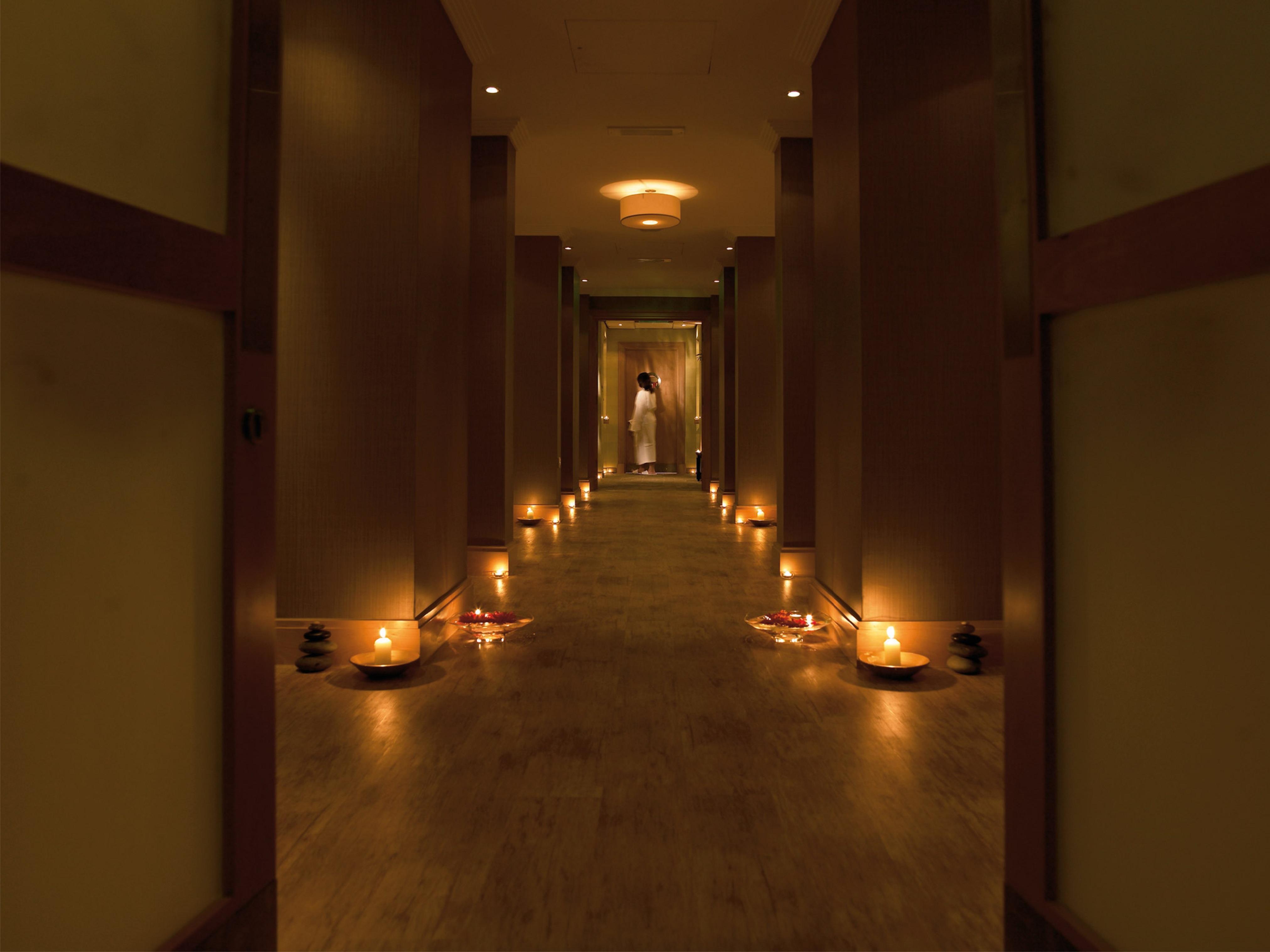Macdonald Bath Spa Hotel Buitenkant foto The photo shows a dimly lit corridor lined with soft lighting. On both sides of the hallway, small candles are placed in bowls, creating a warm and inviting ambiance. At the end of the corridor, there appears to be a person standing, possibly prepari