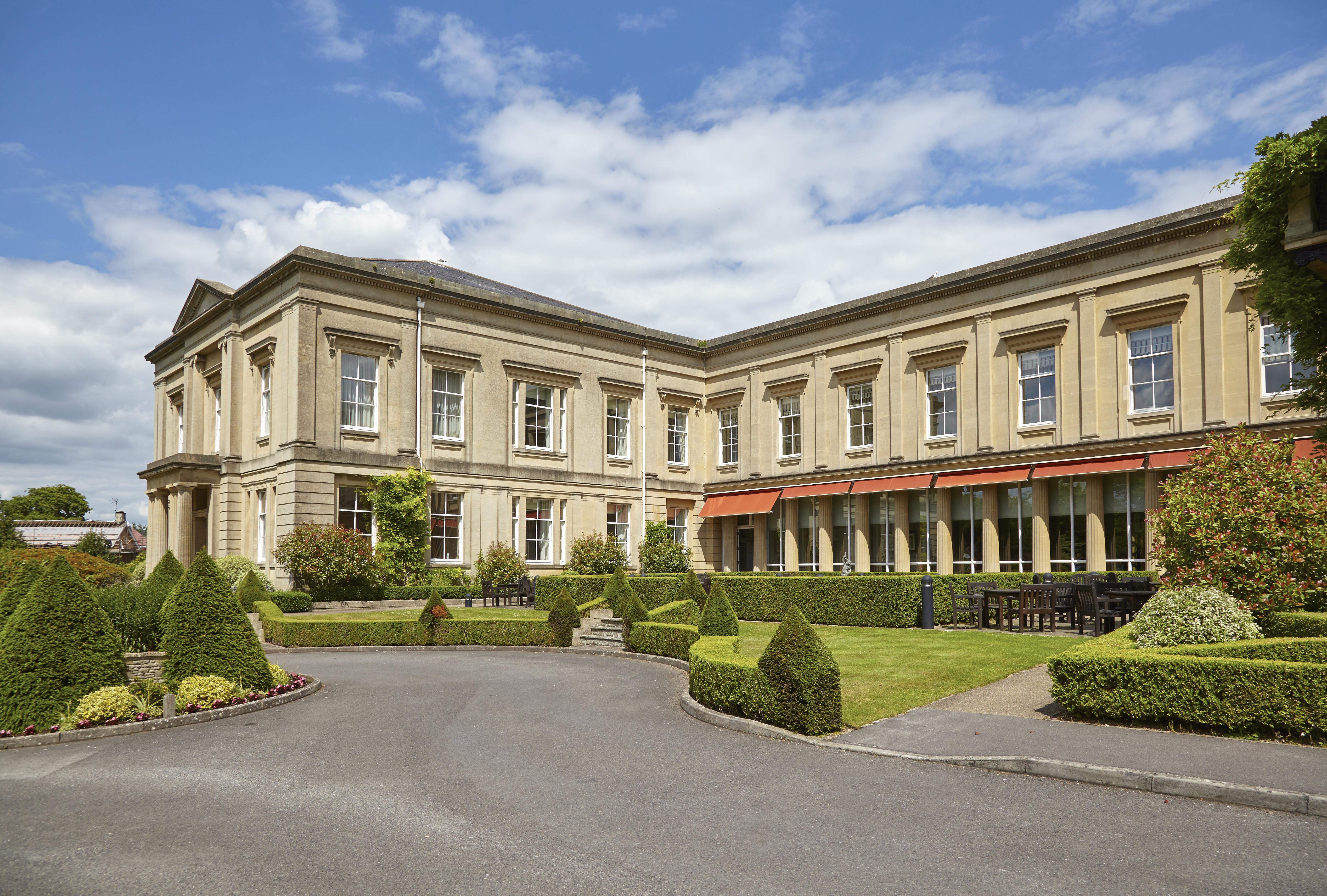 Macdonald Bath Spa Hotel Buitenkant foto The photo depicts a large, elegant building with a classic architectural style, featuring a combination of stone and large windows. The structure appears to have two sections: a main, stately part on the left and an adjoining section that has a terra