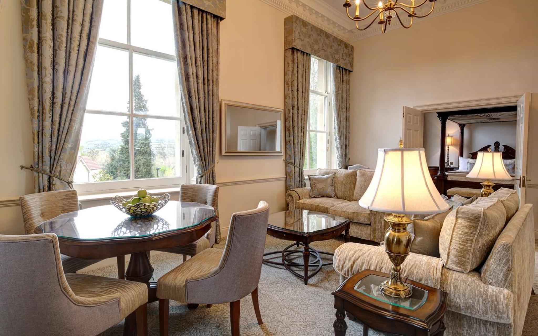 Macdonald Bath Spa Hotel Buitenkant foto The photo displays a beautifully furnished living room. The room features large windows dressed with elegant curtains that allow natural light to flood in. There is a comfortable seating area with a stylish sofa and chairs arranged around a small cof
