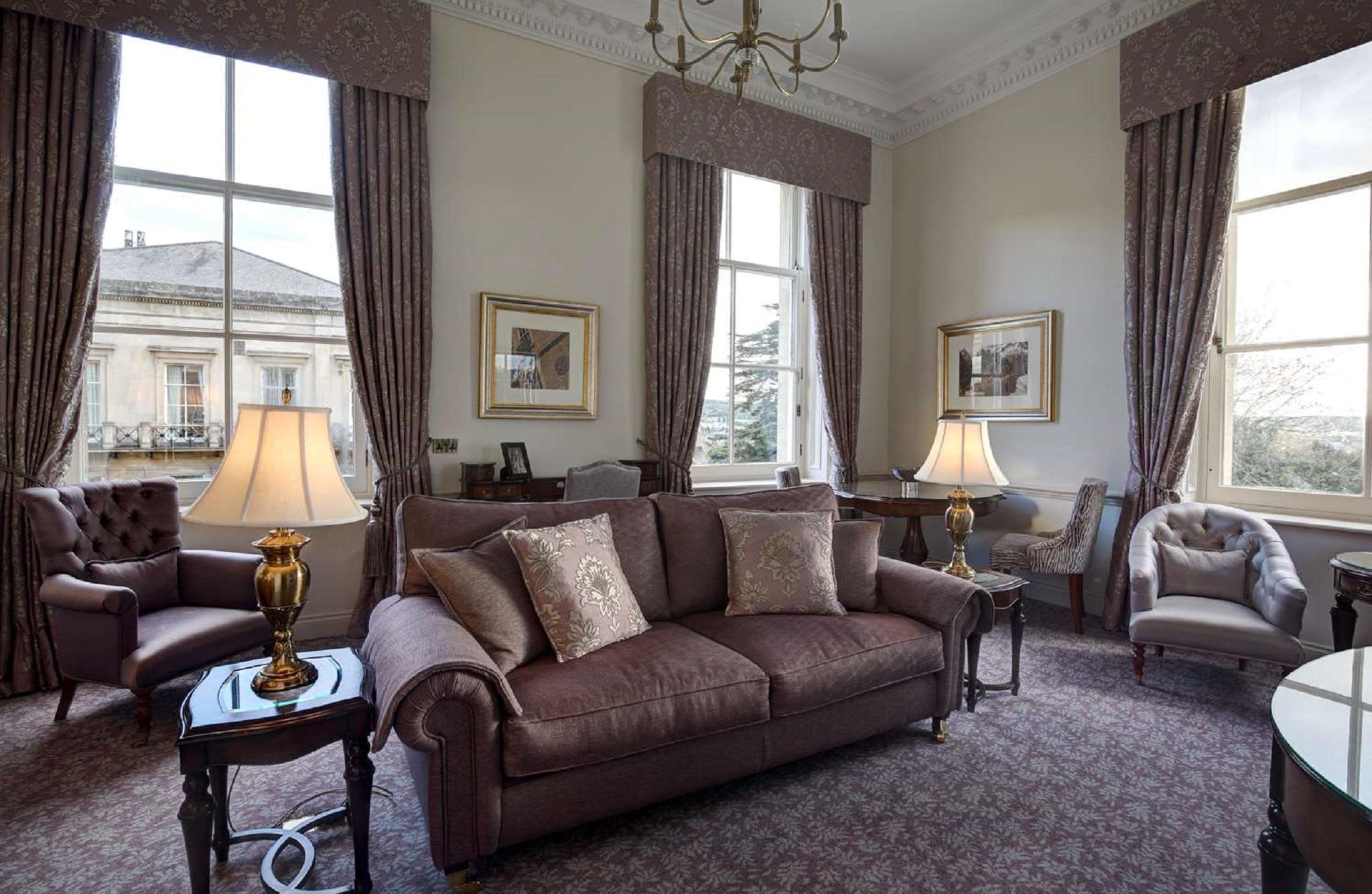 Macdonald Bath Spa Hotel Buitenkant foto The photo shows a well-furnished living room with an elegant and cozy atmosphere. There is a brown couch with decorative pillows in the center. Two armchairs are positioned next to it, with a small table in the middle. The room features large windows