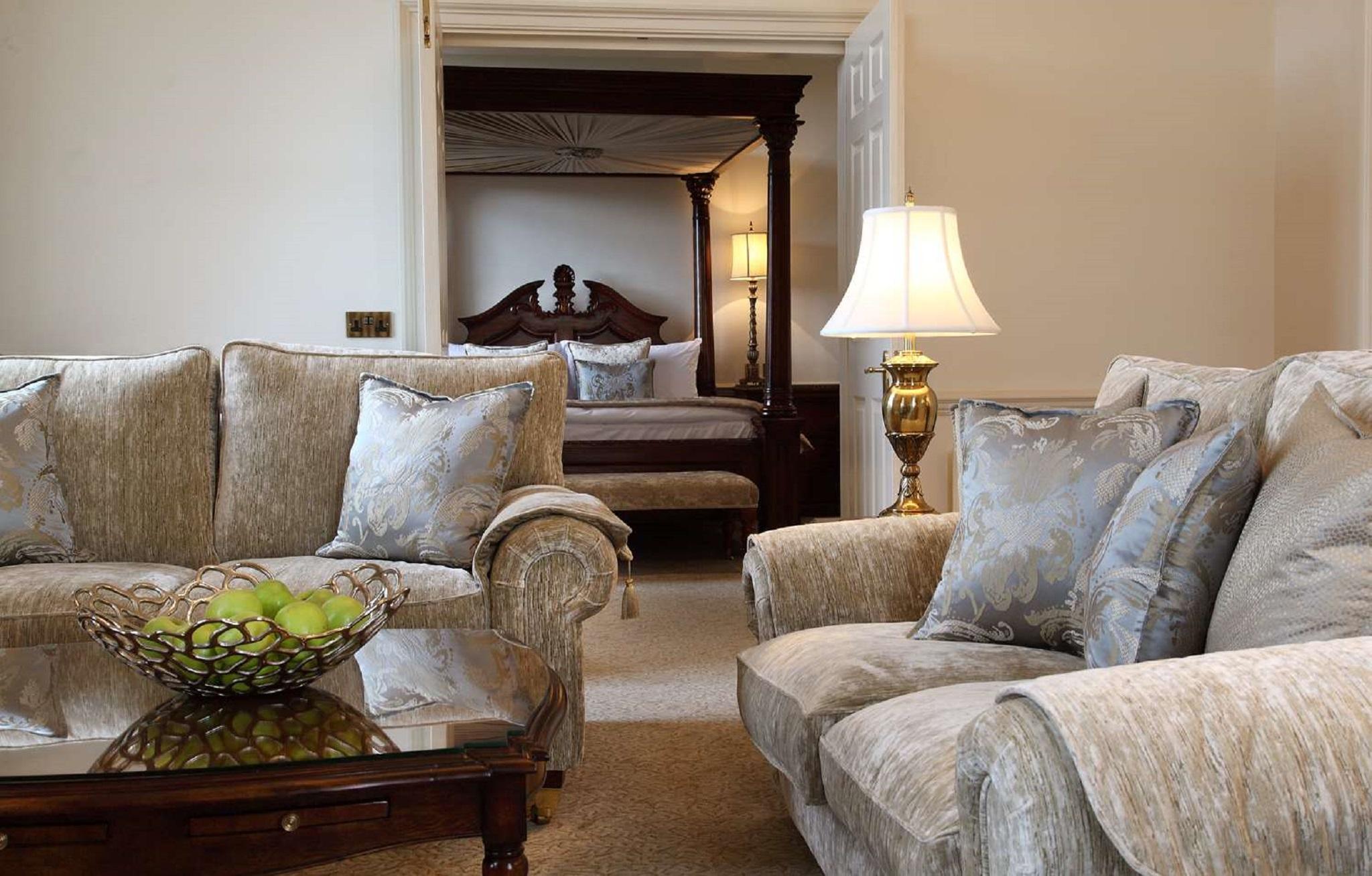 Macdonald Bath Spa Hotel Buitenkant foto The photo shows a cozy living space with elegant furnishings. On the left, there is a sofa with plush cushions and a stylish armchair, both in a soft, light-colored fabric. In the center, there is a decorative glass table with a bowl containing what 