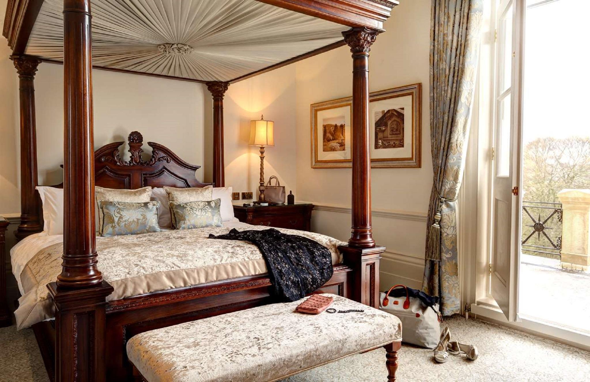 Macdonald Bath Spa Hotel Buitenkant foto The photo depicts a beautifully designed bedroom featuring a four-poster bed with a decorative canopy. The bed is dressed with elegant bedding and several patterned pillows. Adjacent to the bed, there is a matching wooden nightstand with a stylish la