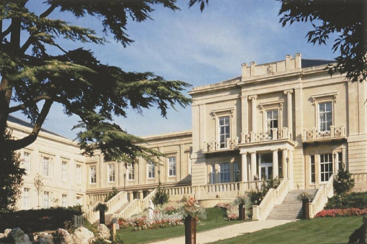 Macdonald Bath Spa Hotel Buitenkant foto The photo depicts an elegant, stately building characterized by classical architecture. It features a symmetrical facade with large windows and decorative balconies. The structure is complemented by a lush green lawn and landscaped gardens, enhancing